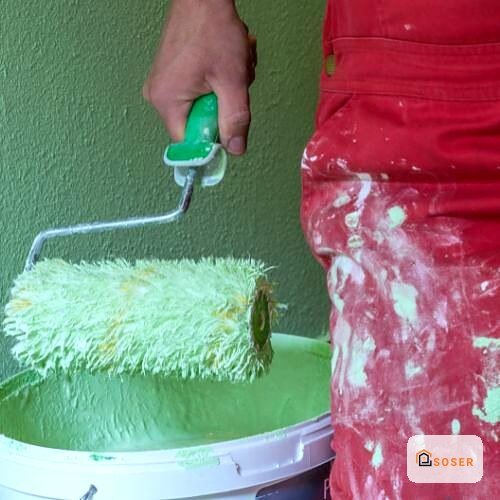 Applicazione di pittura verde con rullo su parete durante imbiancatura