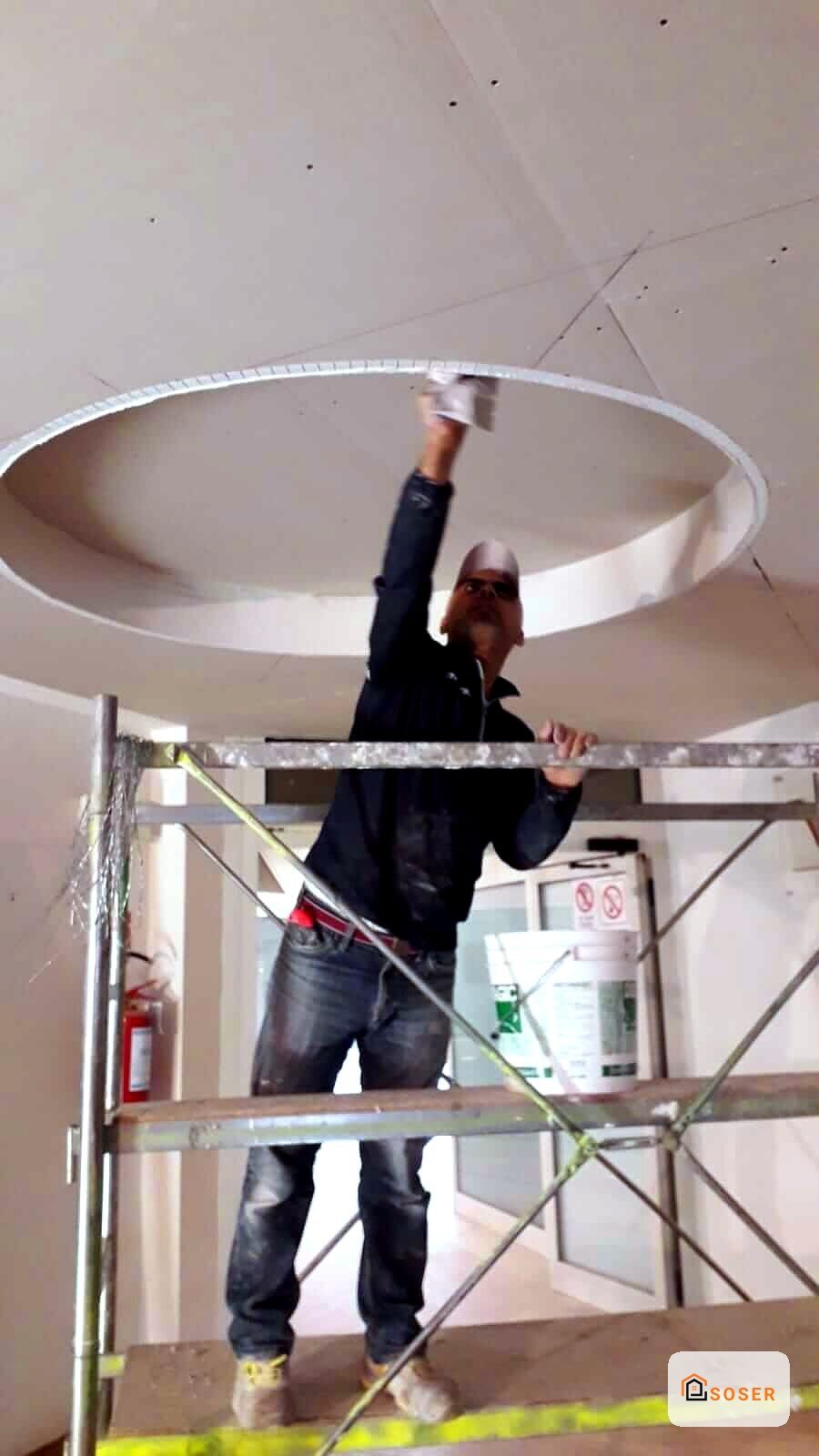 Operaio su ponteggio installa controsoffitto in cartongesso con grande lucernario circolare