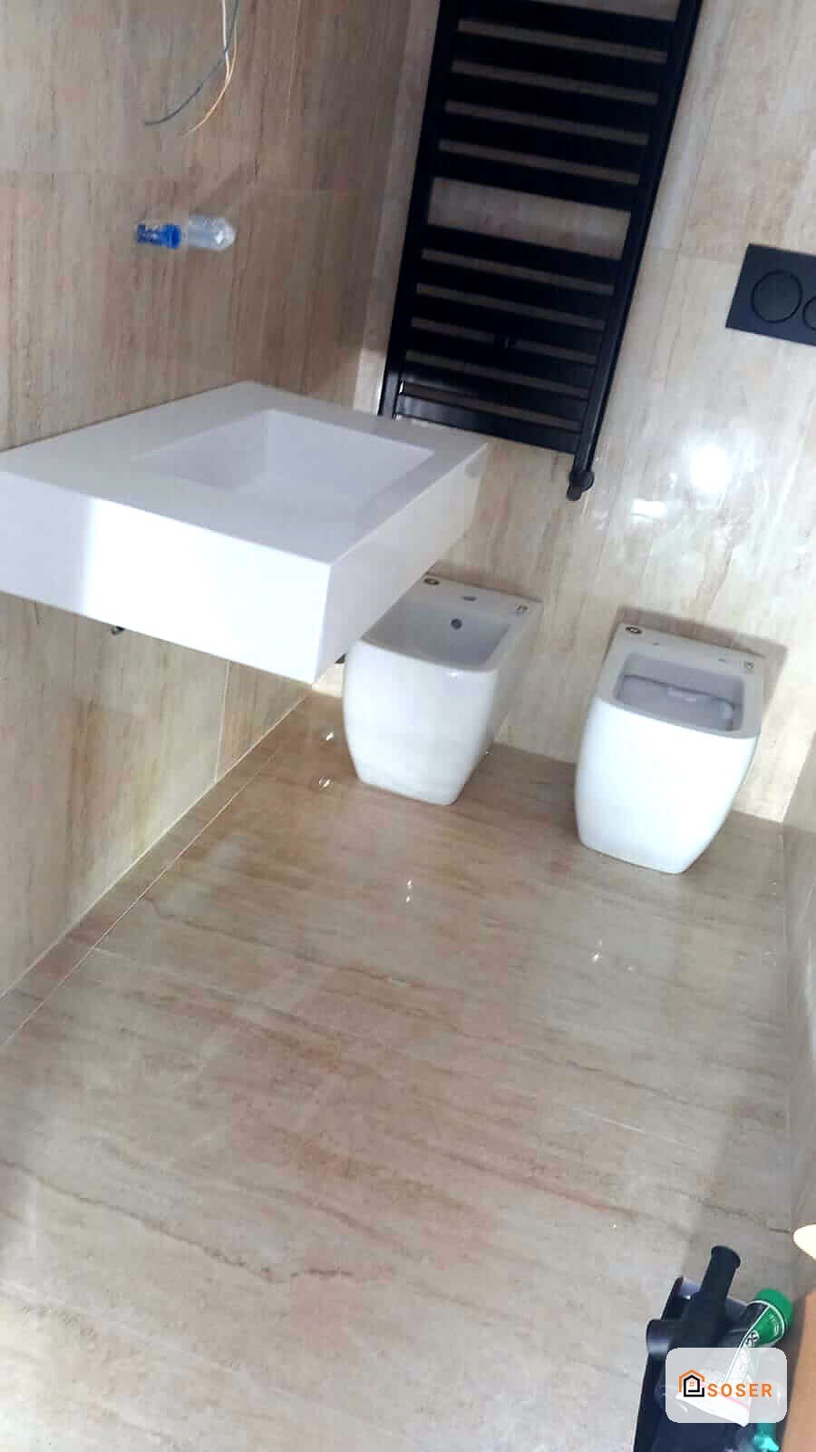 Bagno in ristrutturazione con nuova vasca bianca, sanitari e radiatore scaldasalviette nero