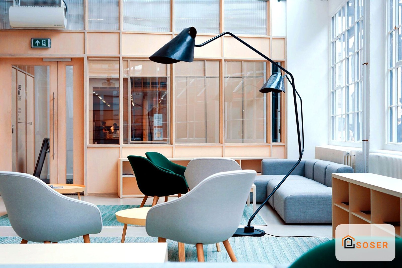 Sala d'attesa moderna con sedie grigie e verdi, grande lampada ad arco nera e infissi in legno naturale