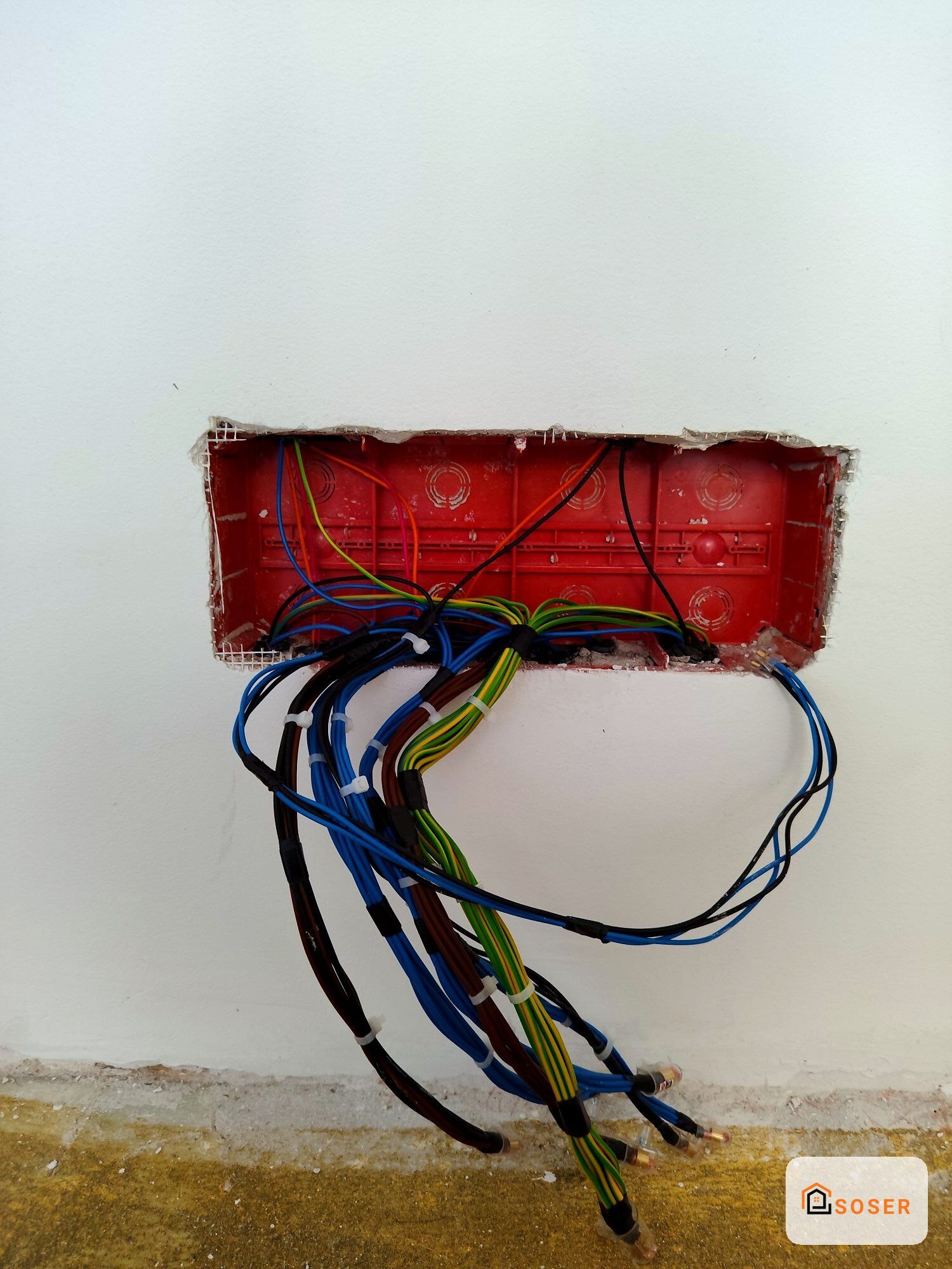 Scatola elettrica rossa a incasso con cavi colorati in fase di installazione impianto elettrico