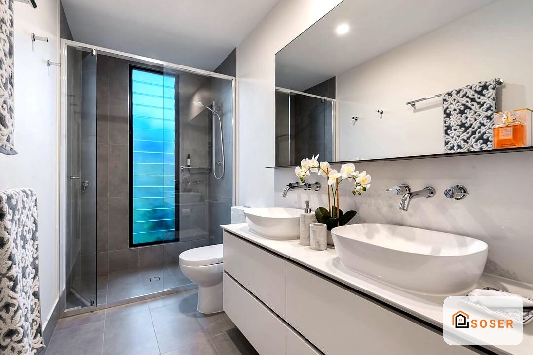 Bagno moderno con doppio lavabo bianco, specchio grande, doccia con vetro blu e piastrelle grigie