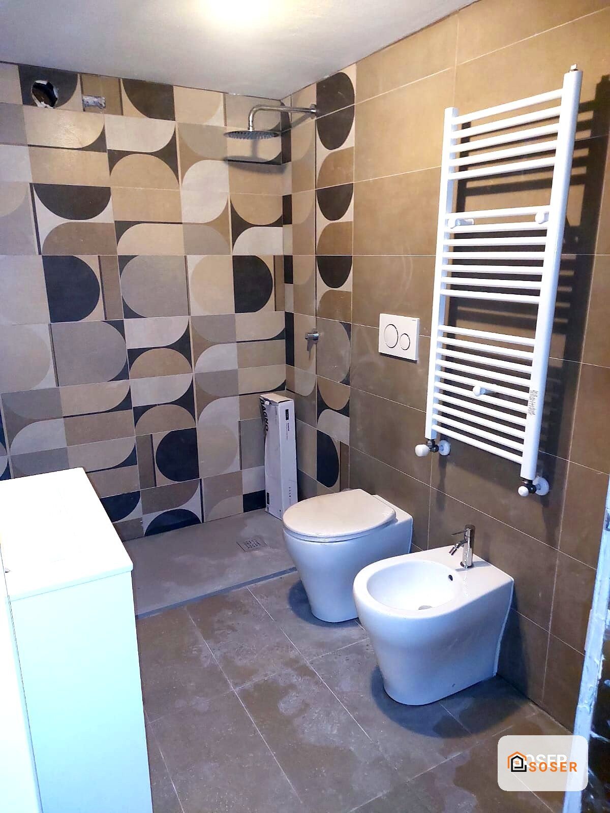 Bagno moderno ristrutturato con piastrelle geometriche, toilet sospeso, bidet e scaldasalviette bianco