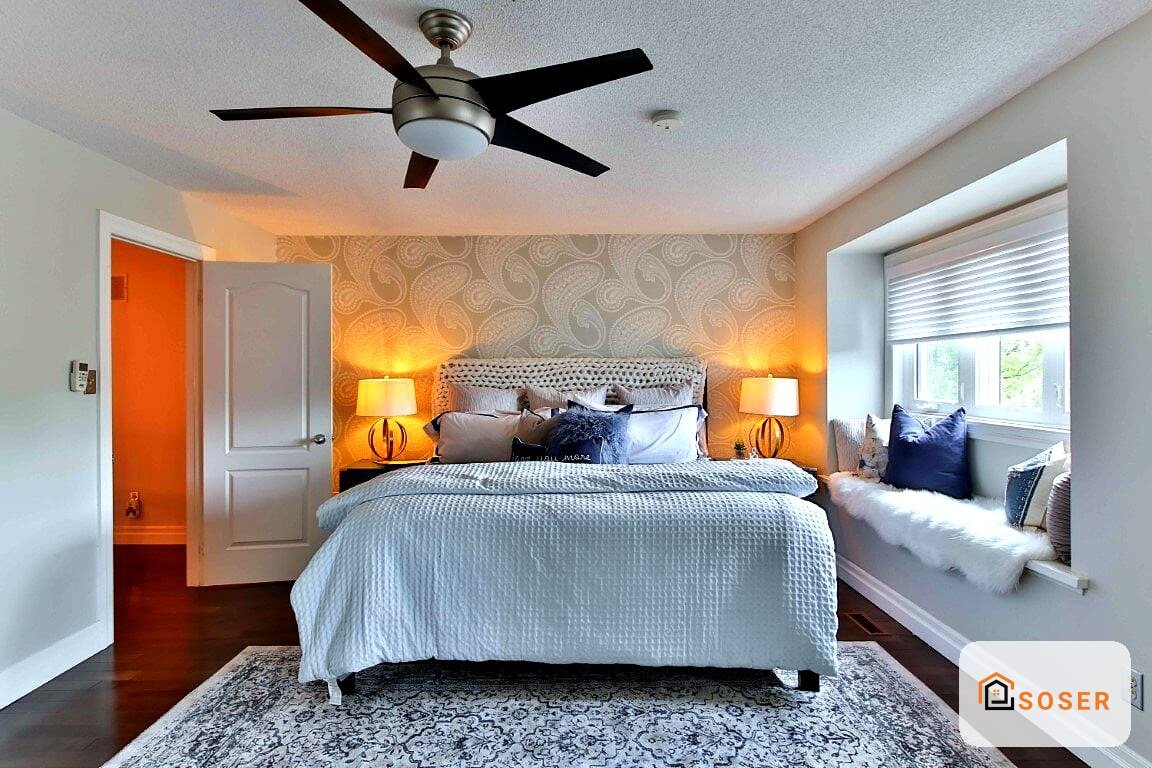 Camera da letto moderna con pareti arancioni, letto con testata grigia, lampade ambrate e ventilatore a soffitto