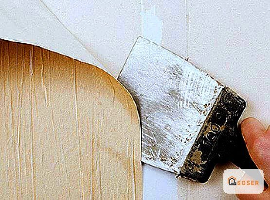 Pennello con vernice bianca su parete durante lavori di imbiancatura e pittura