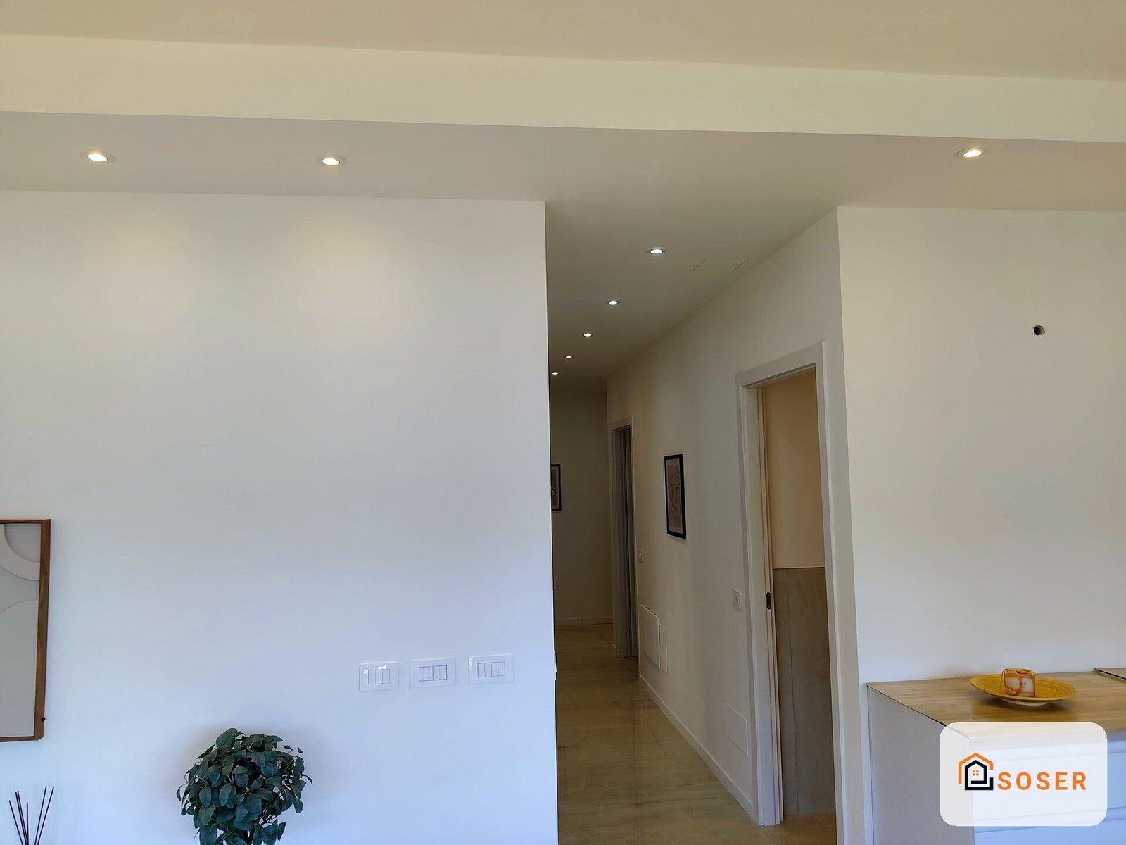 Interno moderno con pareti bianche, cartongesso, corridoio e porta, illuminazione a incasso