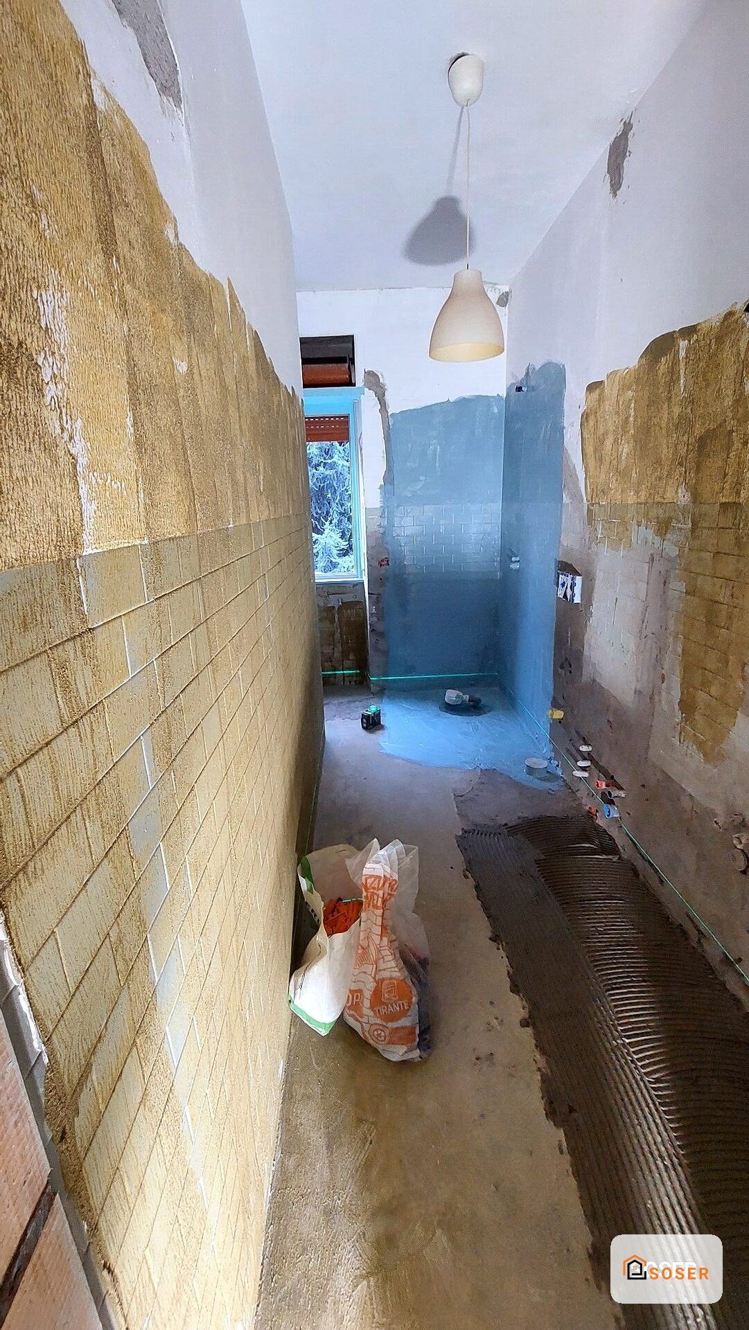 Interno di appartamento in ristrutturazione con pavimento in piastrelle e pareti azzurre, prima dei lavori di finitura