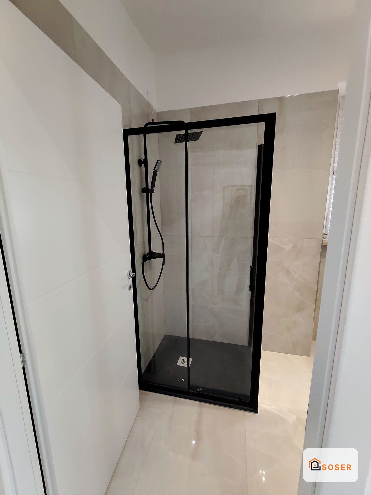 Doccia moderna con box doccia nero e parete in piastrelle bianche in bagno ristrutturato