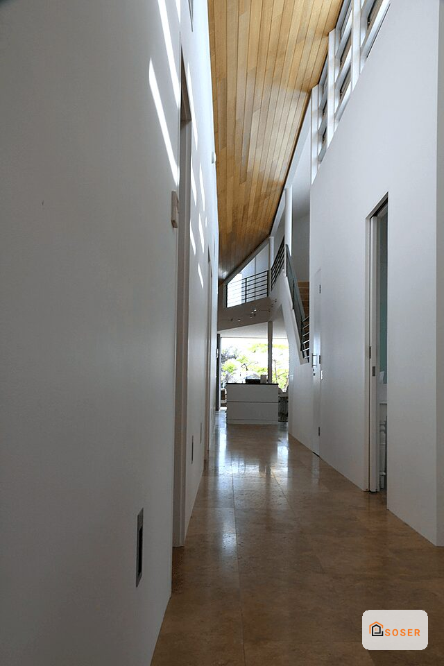 Corridoio moderno con pareti bianche, soffitto in legno e pavimento in cotto dopo ristrutturazione