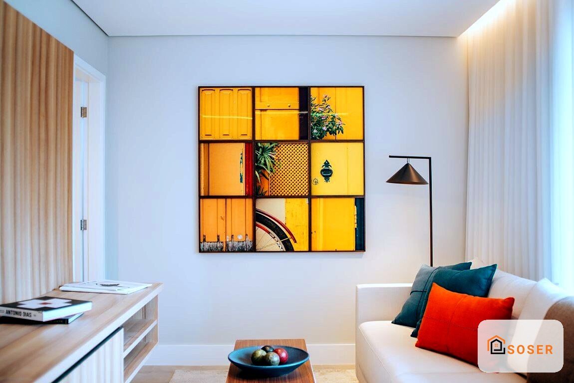 Soggiorno moderno con parete azzurra, quadro artistico giallo e arancione, divano bianco con cuscini colorati