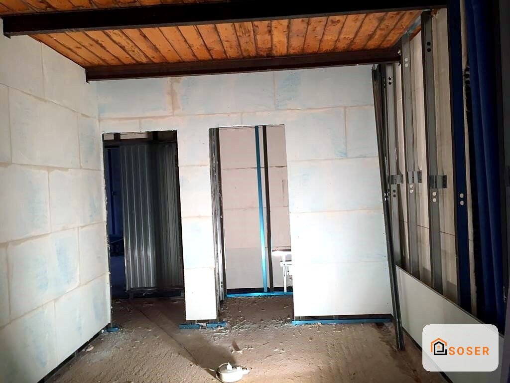 Interno in fase di ristrutturazione con pareti in cartongesso, pavimento in cemento e infissi in alluminio