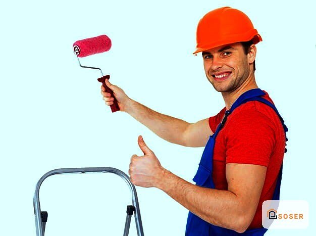 Operaio con casco rosso e rullo di pittura durante lavori di imbiancatura