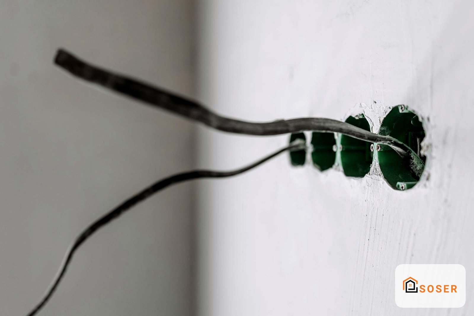 Presa elettrica incassata in muro bianco con cavi neri in uscita