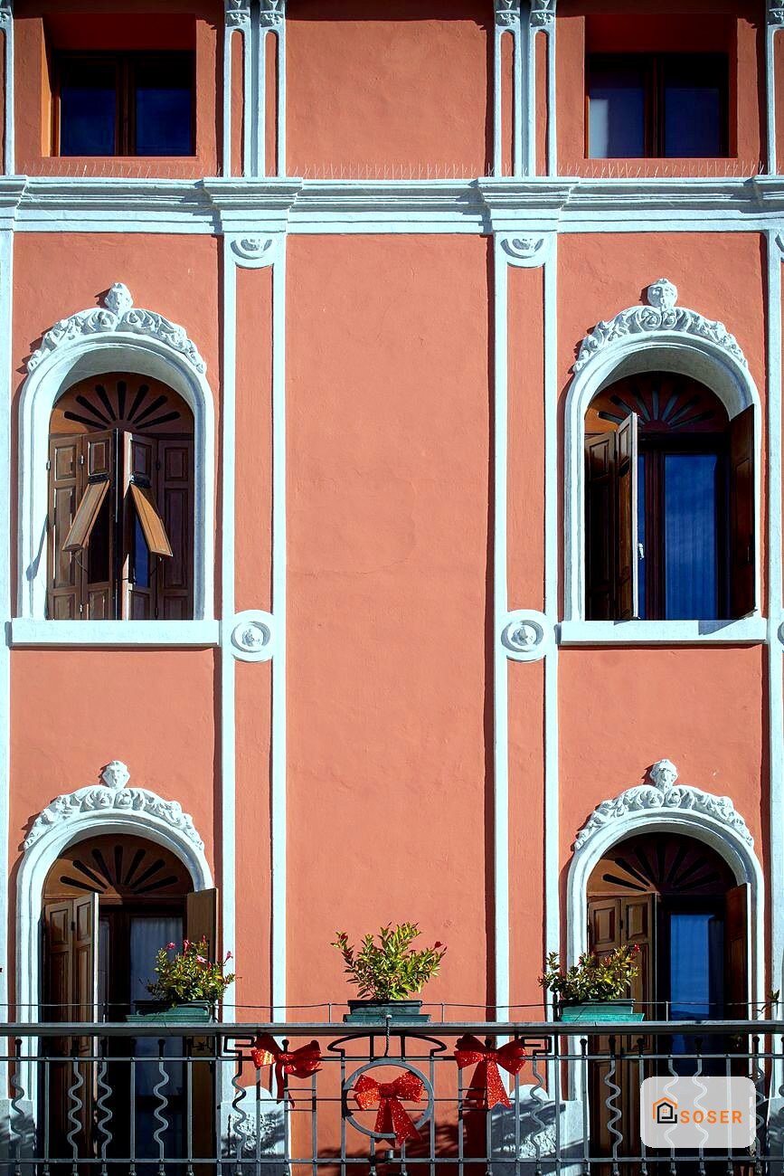 Facciata in stile coloniale con intonaco rosso terracotta, cornici bianche e archi decorativi