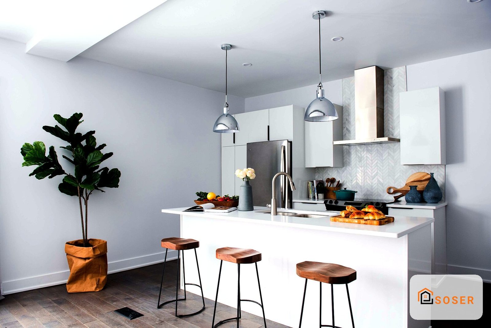 Cucina moderna con isola bianca, sgabelli in legno e pendenti cromati