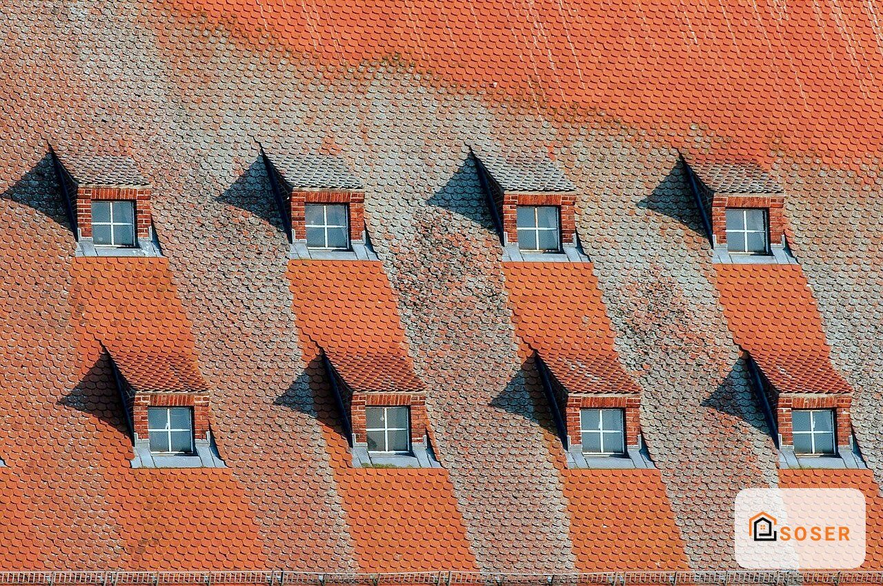 Facciata in laterizio con pattern geometrico rosso e grigio, finestre con cornici in mattoni e tetti spioventi