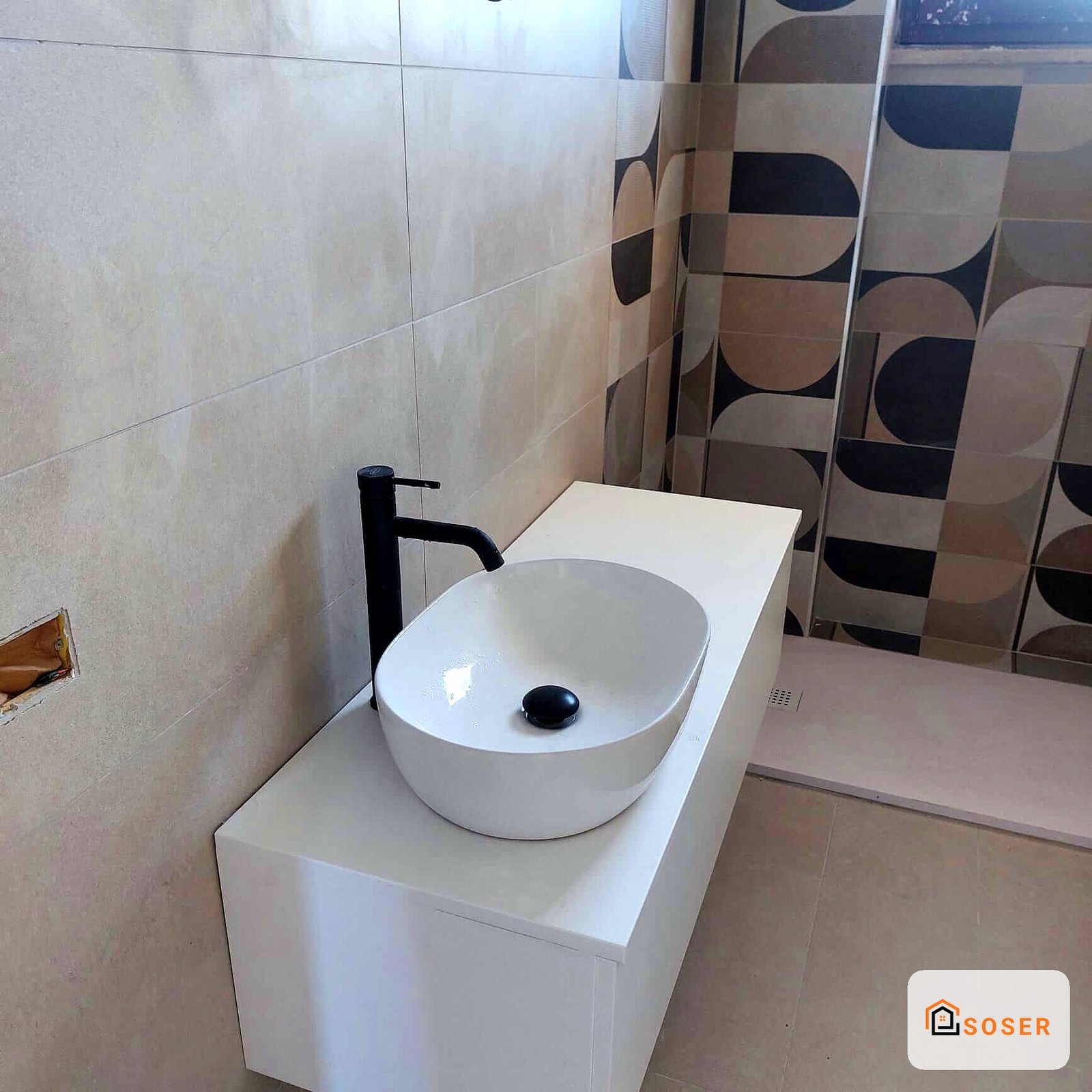 Bagno moderno con lavabo bianco rotondo e rubinetteria nera su mobile in stile contemporaneo