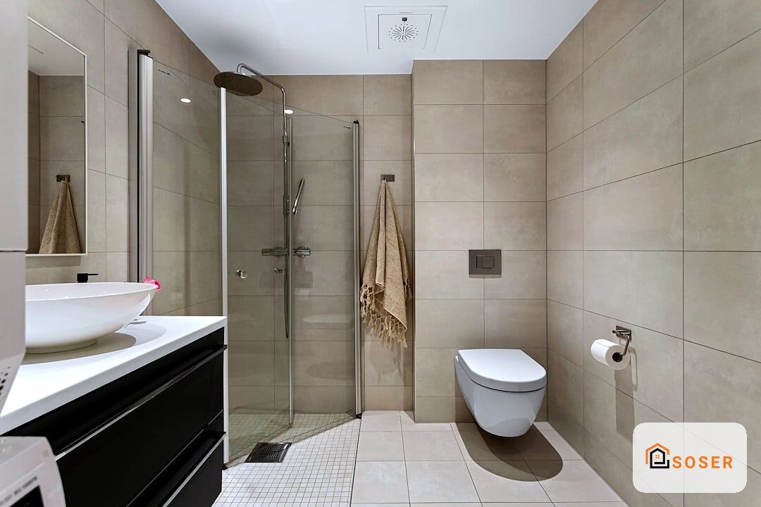 Bagno moderno ristrutturato con doccia in vetro, lavabo bianco e piastrelle beige a Milano
