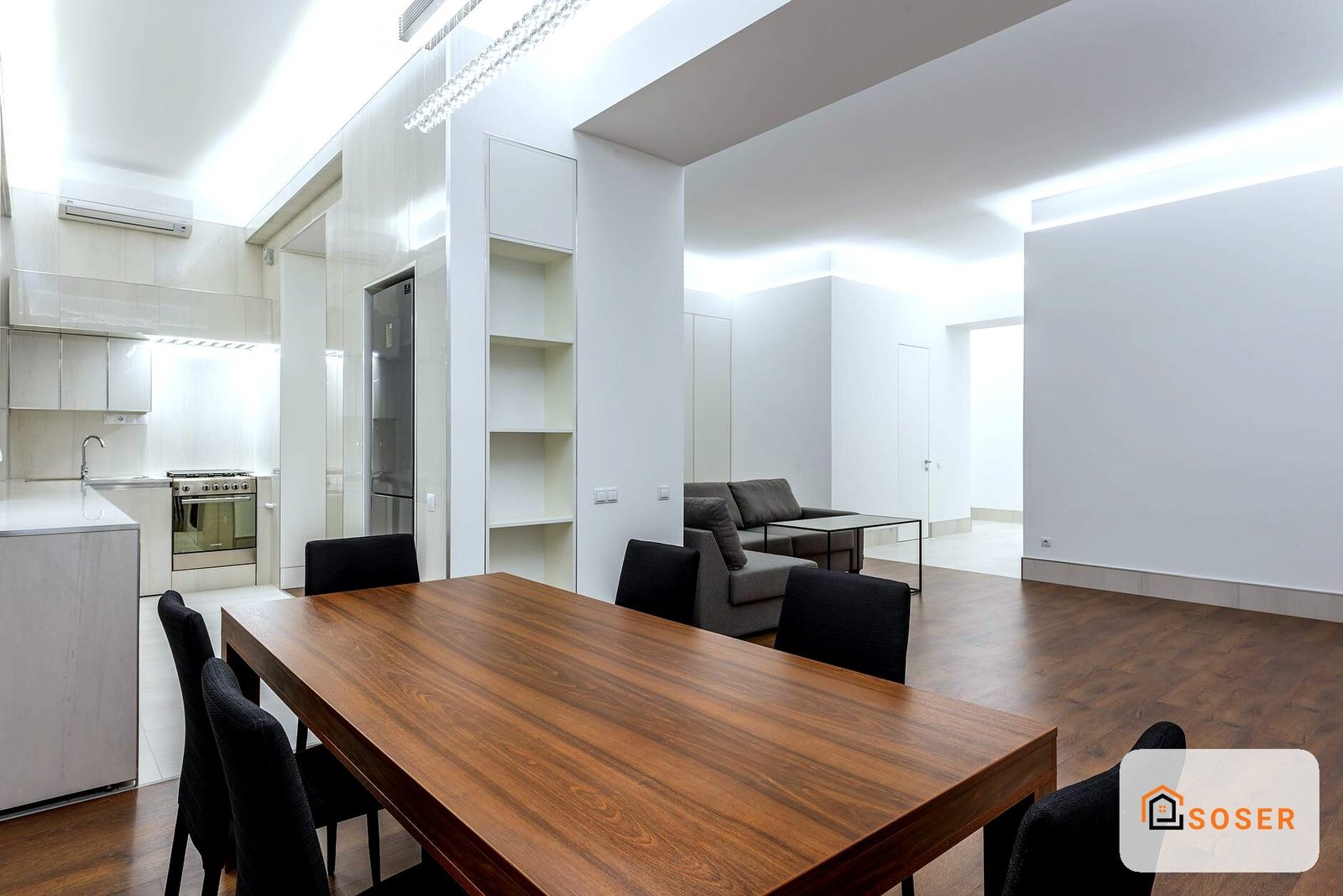 Soggiorno moderno con tavolo in legno, cucina integrata e living arredato con mobili design