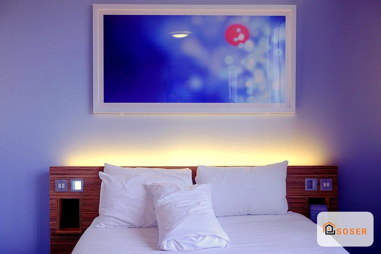 Camera da letto moderna con parete blu, letto bianco e quadro luminoso sulla parete