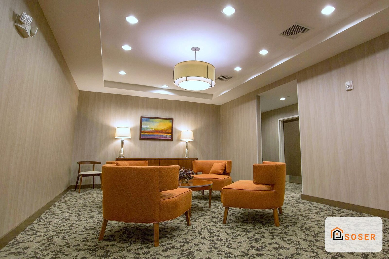 Sala d'attesa moderna con divani arancioni e illuminazione a incasso, pareti in carta da parati beige