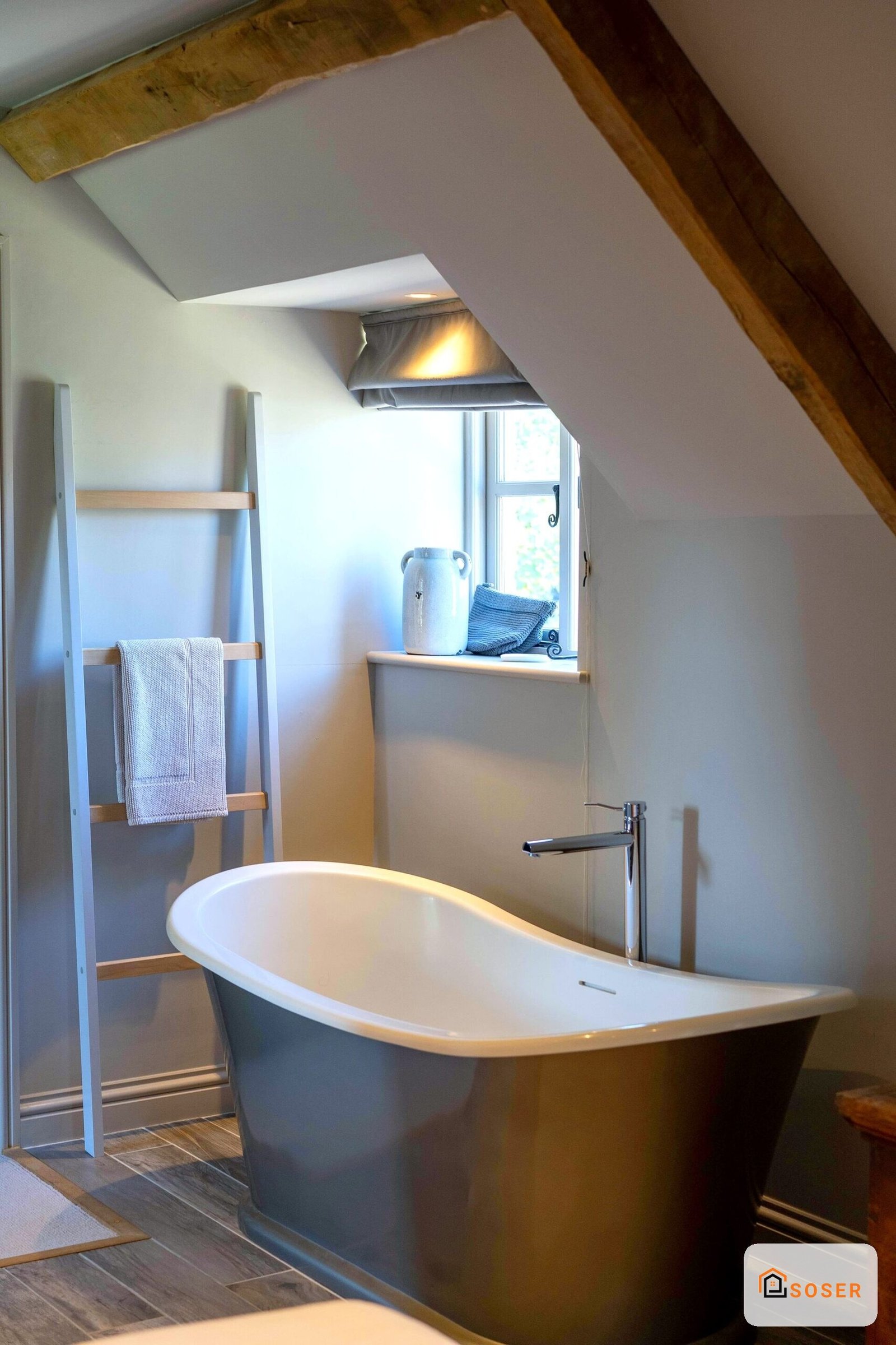 Bagno mansardato moderno con vasca freestanding grigia e legno a vista in sottotetto