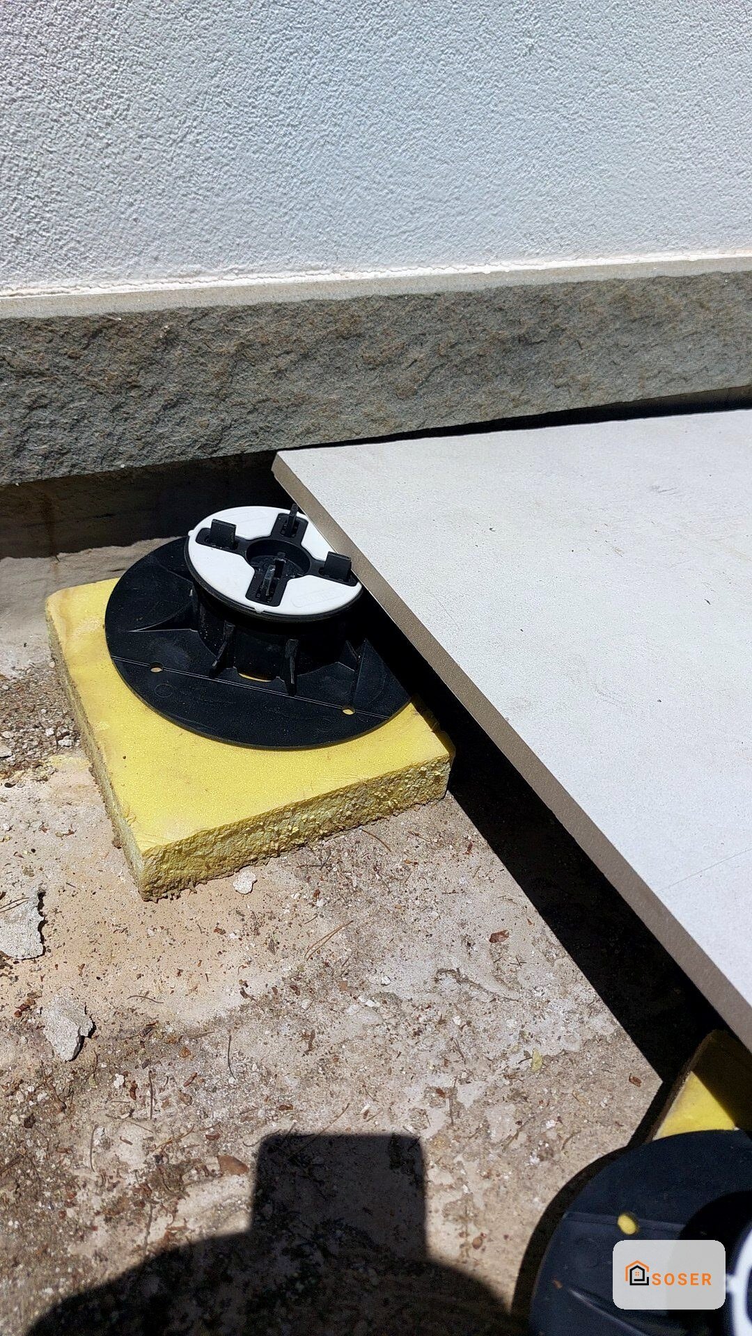 Supporto regolabile giallo con base nera per livellamento pavimenti in cantiere edile