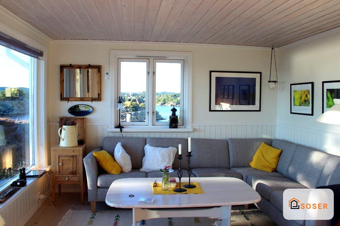 Soggiorno moderno con divano grigio, infissi in legno e vista sul lago, arredamento contemporaneo