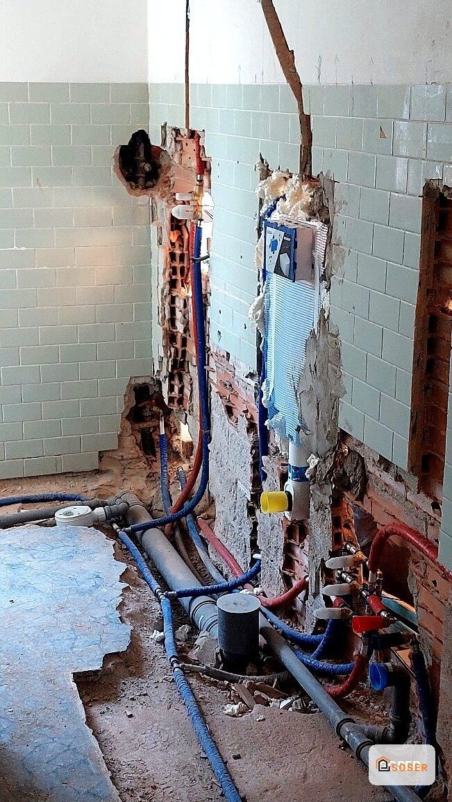 Impianto idraulico e elettrico in fase di demolizione e ristrutturazione in bagno con tubi blu e rossi