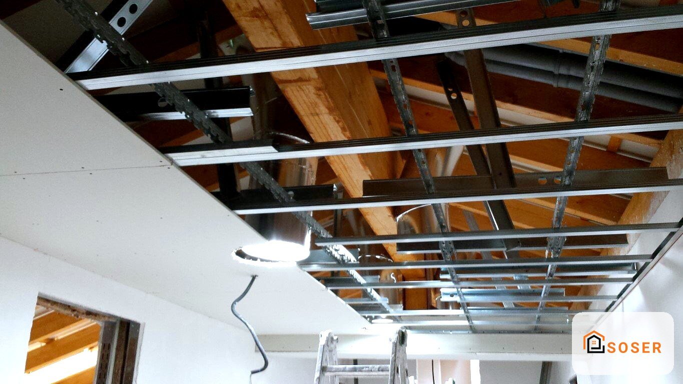 Controsoffitto in cartongesso in fase di installazione con struttura metallica e travi in legno visibili