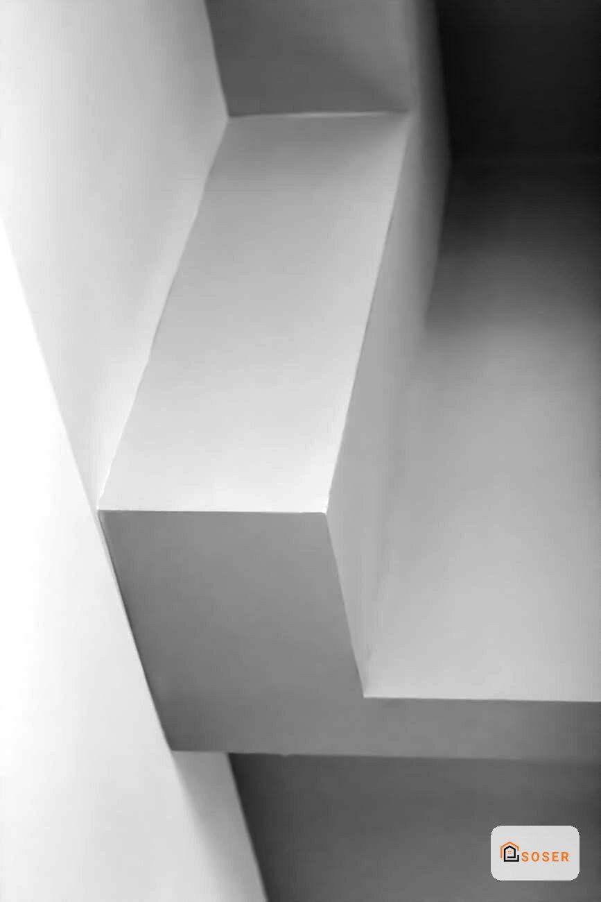 Dettaglio di pareti in cartongesso con finiture moderne e giochi di luce in bianco e grigio