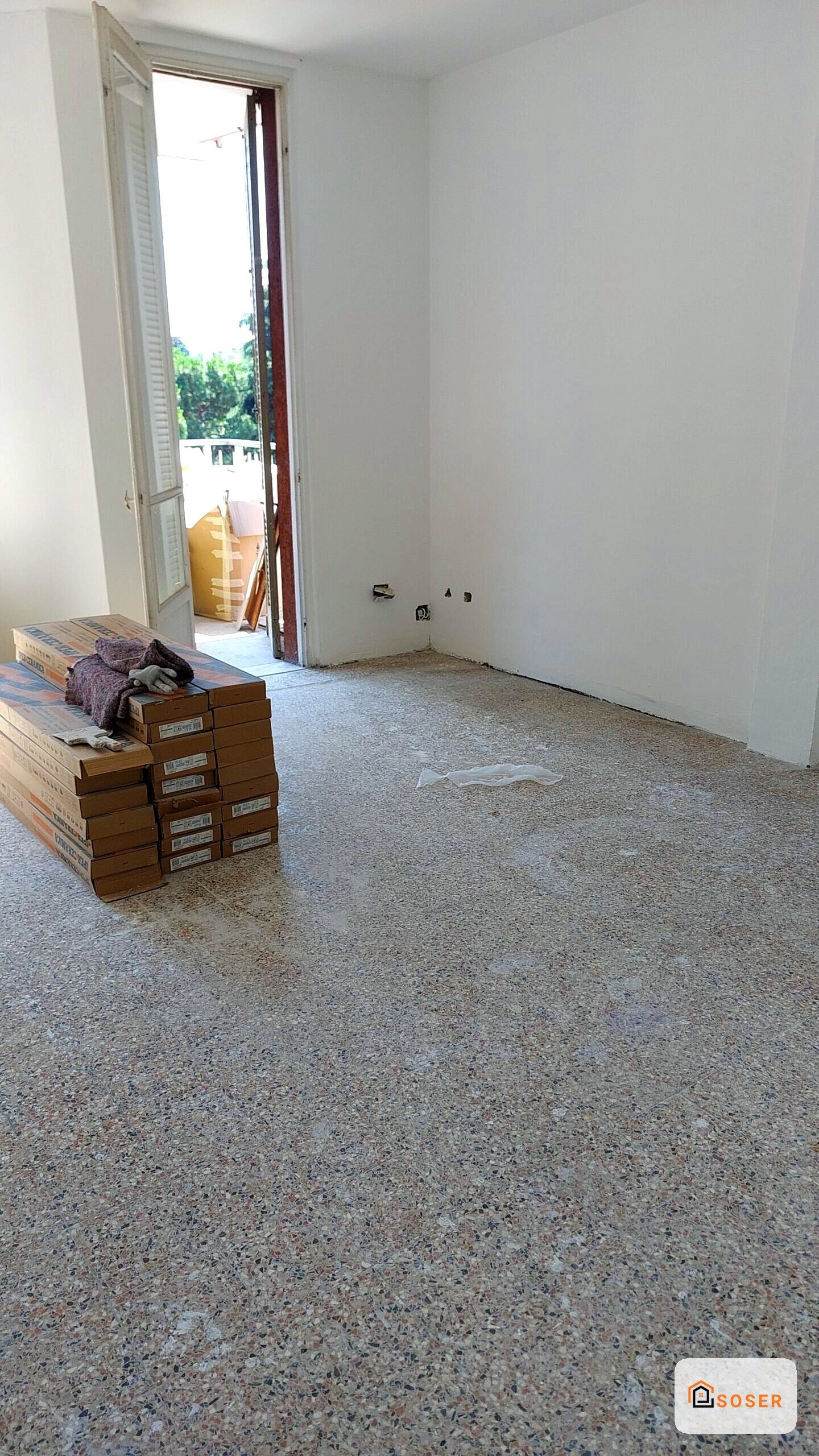Stanza vuota in ristrutturazione con pavimento in cemento e pareti bianche intonacate