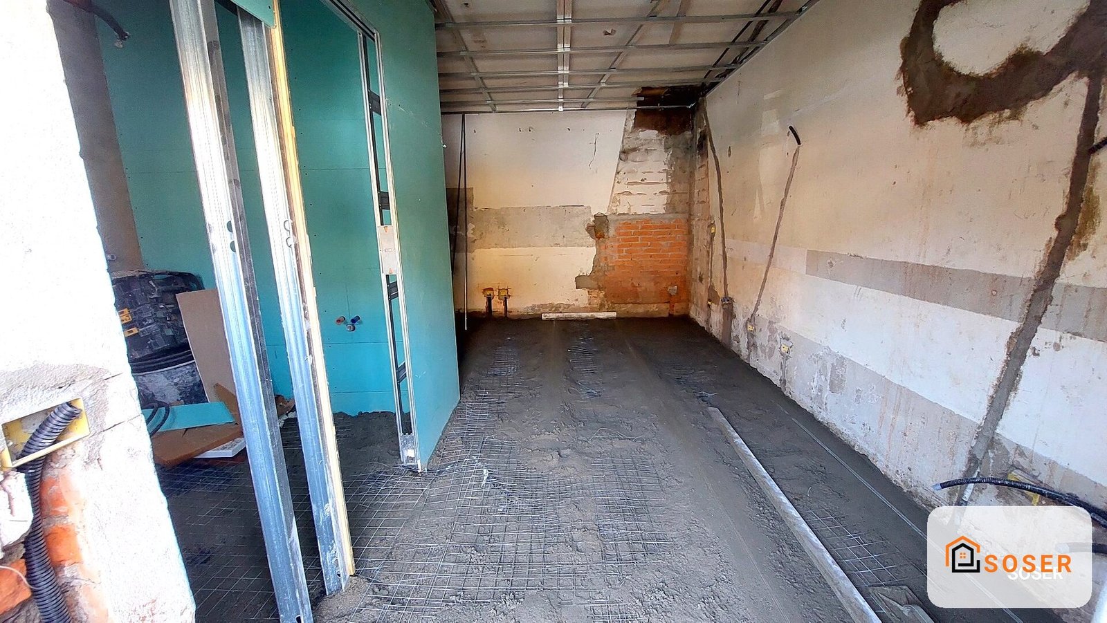 Interno di locale in ristrutturazione con pareti danneggiate e pavimento in cemento
