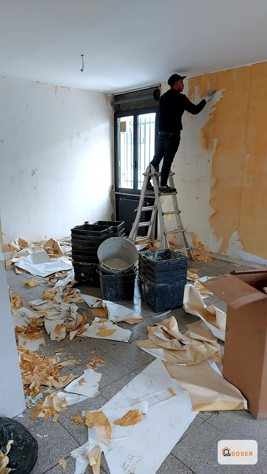 Operaio su scala durante demolizione e rimozione intonaco in appartamento in ristrutturazione a Milano