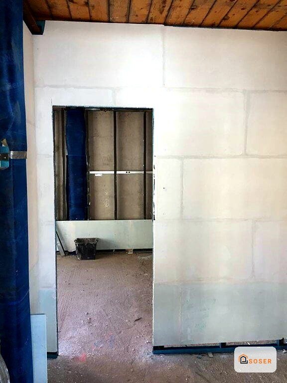 Stanza in fase di ristrutturazione con pareti in cartongesso bianco e porta interna con infissi