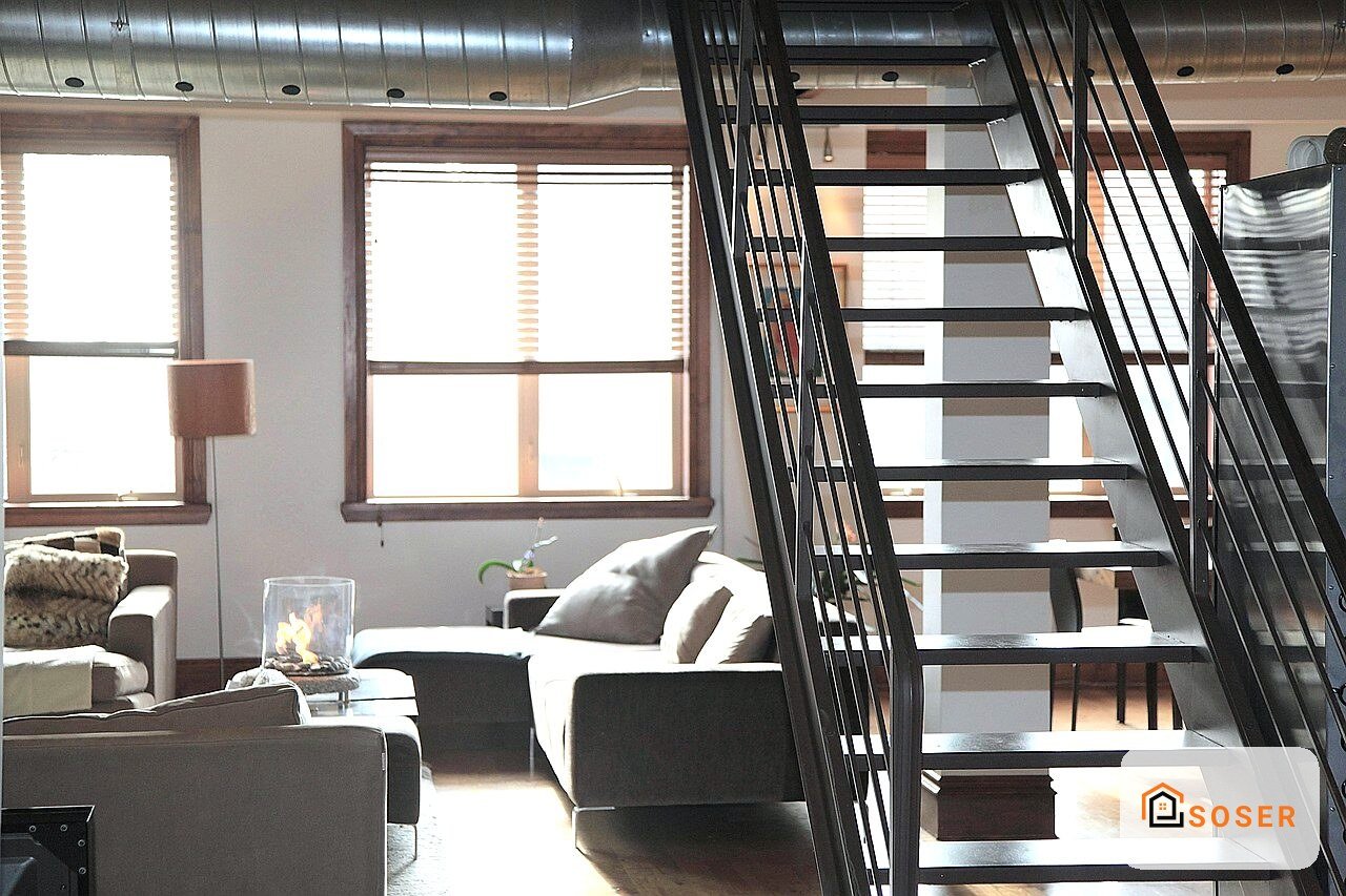 Loft moderno con scala in ferro nero, soggiorno luminoso e finestre ampie a Milano