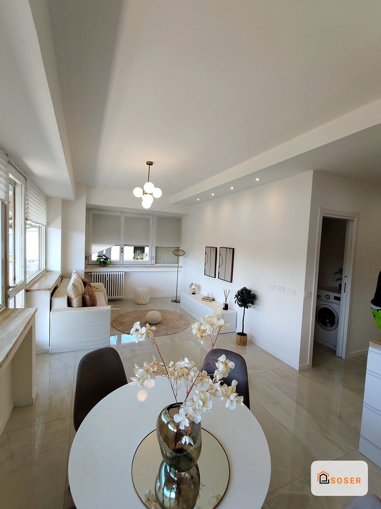 Interno moderno luminoso con cucina a vista, pavimenti in gres porcellanato e arredo minimalista