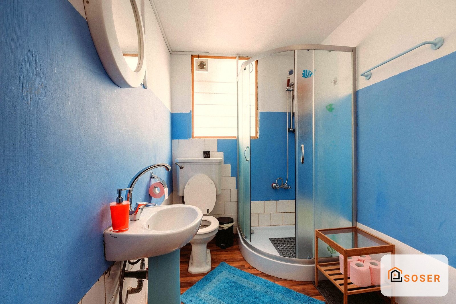 Bagno moderno con piastrelle blu e bianche, lavabo rotondo e doccia angolare