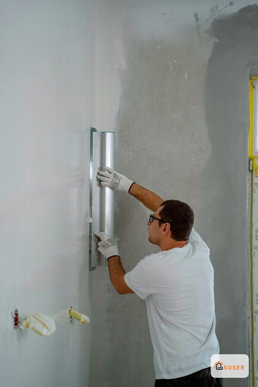 Operaio applica stucco su parete interna con spatola metallica durante lavori di cartongesso