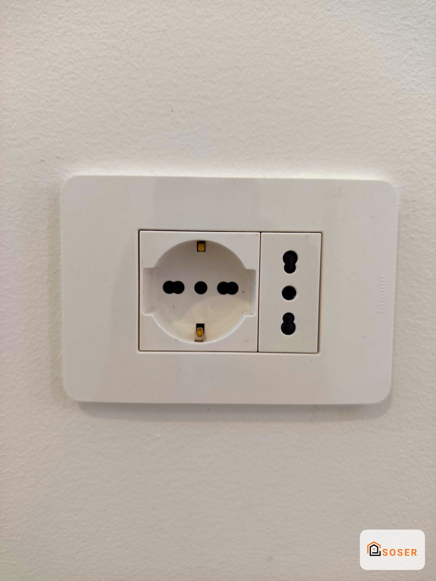 Presa elettrica schuko e interruttori bianchi su parete con finitura in imbiancatura