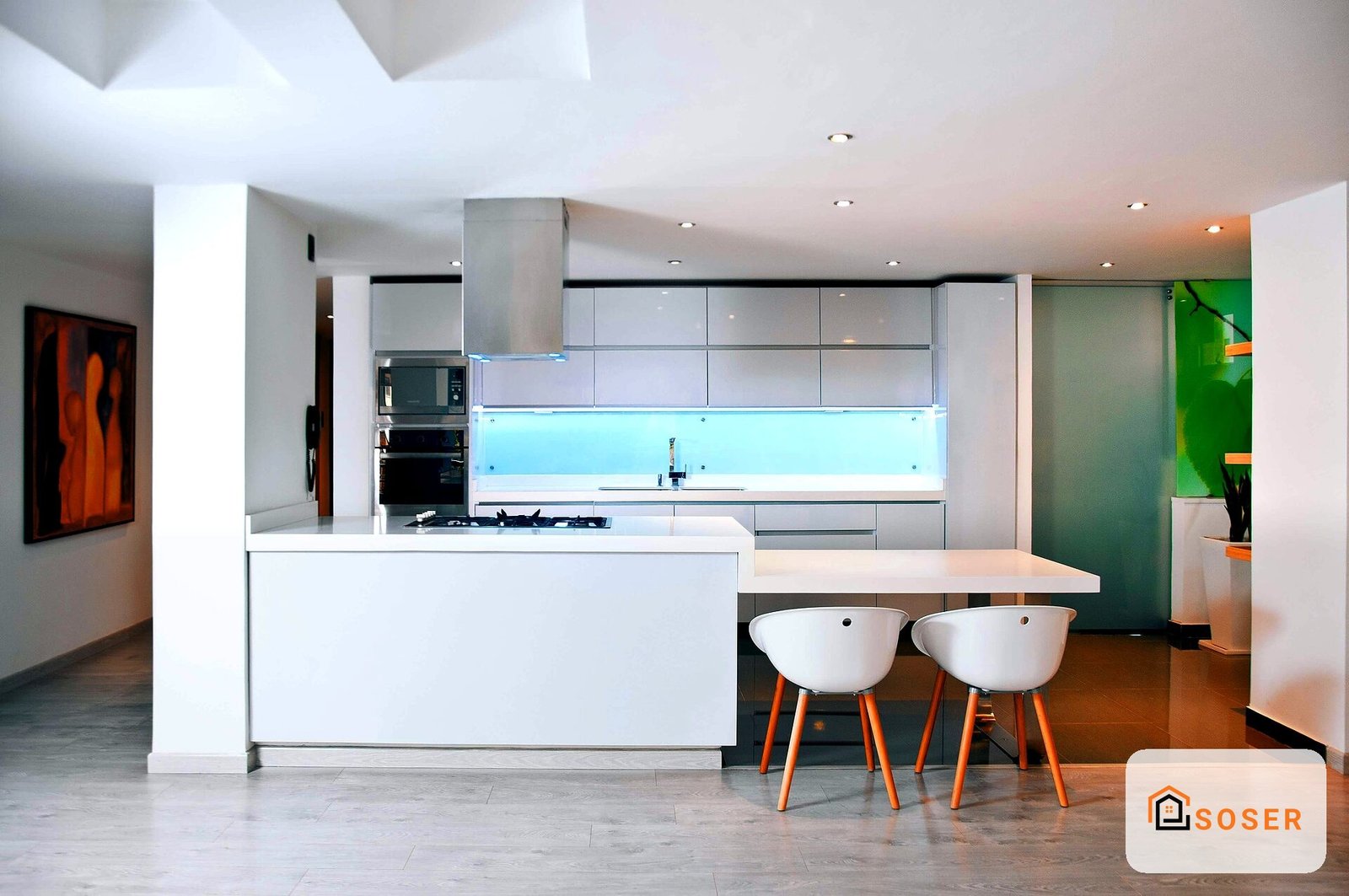 Cucina moderna con isola centrale, cappe grigie e sgabelli bianchi con gambe arancioni