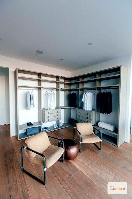 Elegante cabina armadio con scaffalature in legno chiaro e sedie moderne in una villa a Milano