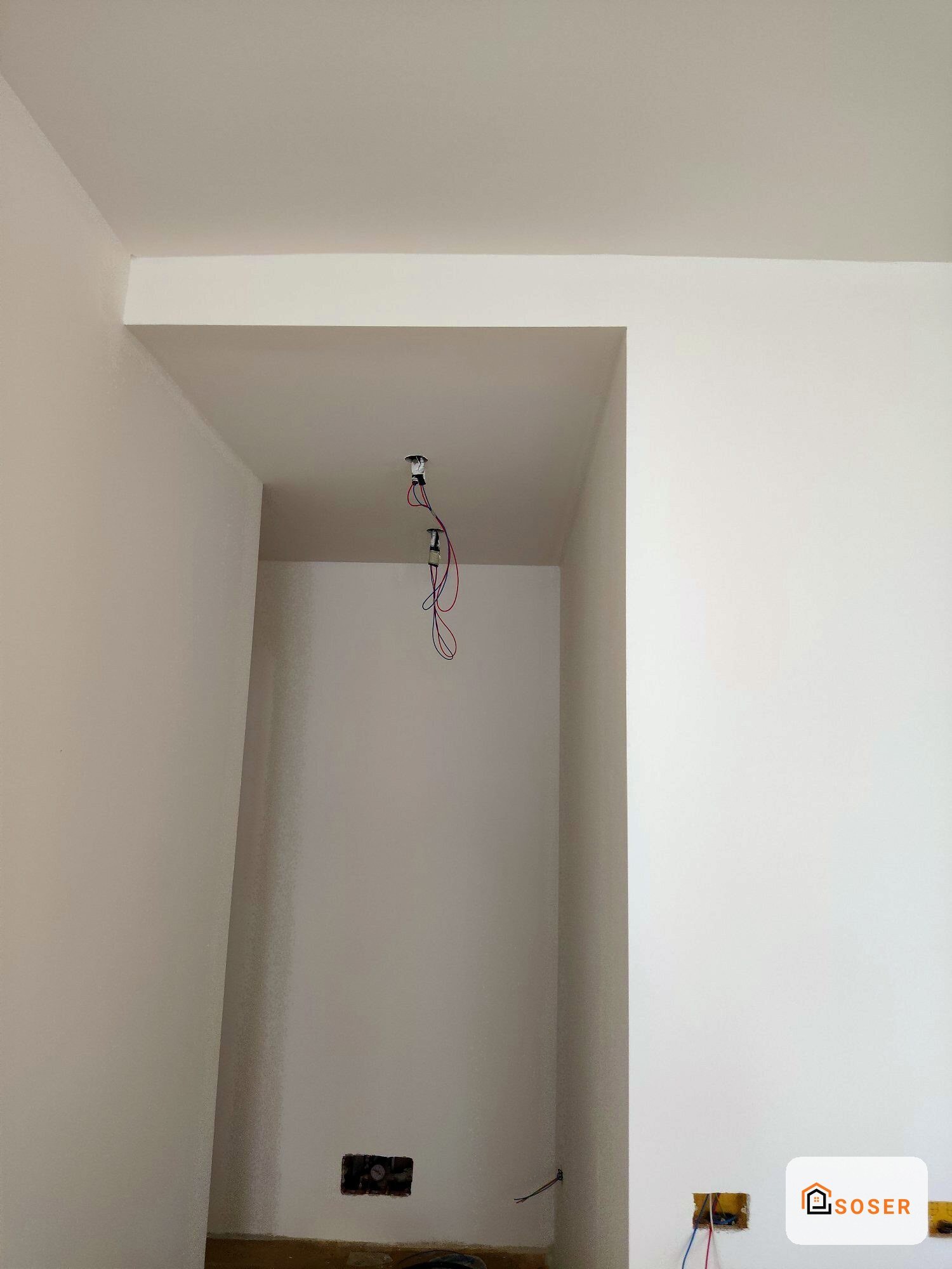 Nicchia in cartongesso con impianto elettrico in fase di allestimento, pareti bianche e cavi colorati