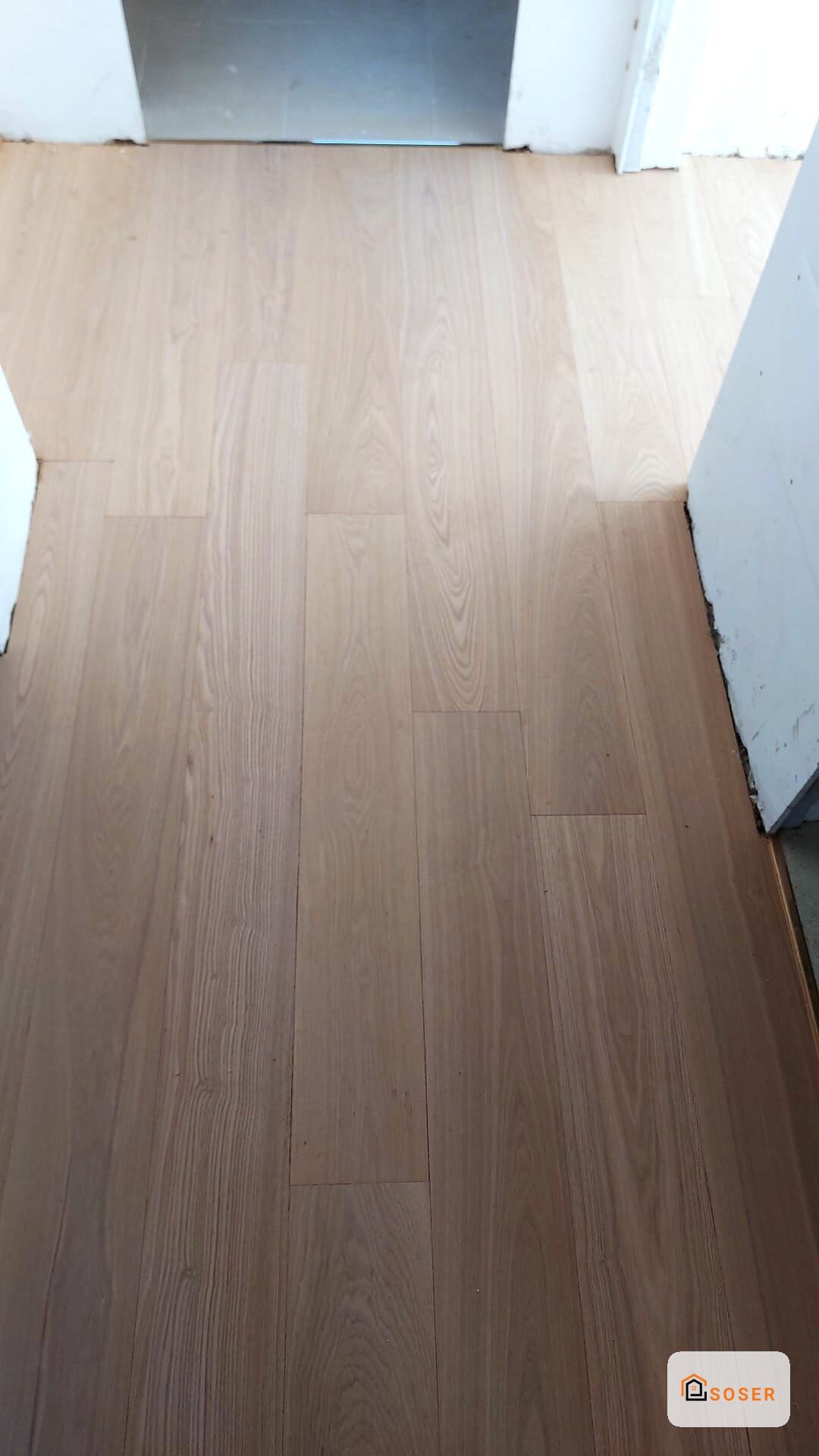 Pavimento in laminato effetto legno chiaro in fase di posa in un'abitazione a Milano
