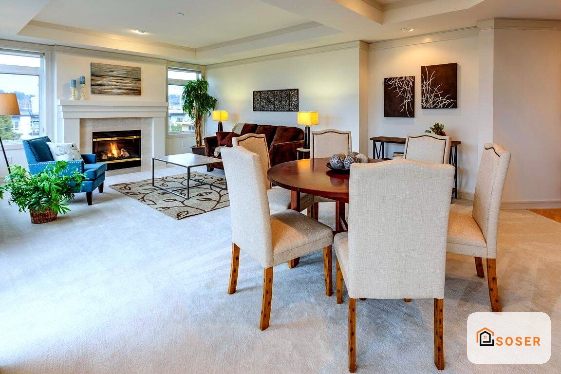 Elegante soggiorno con camino acceso, dining room in legno, sedie beige e pavimenti in parquet.