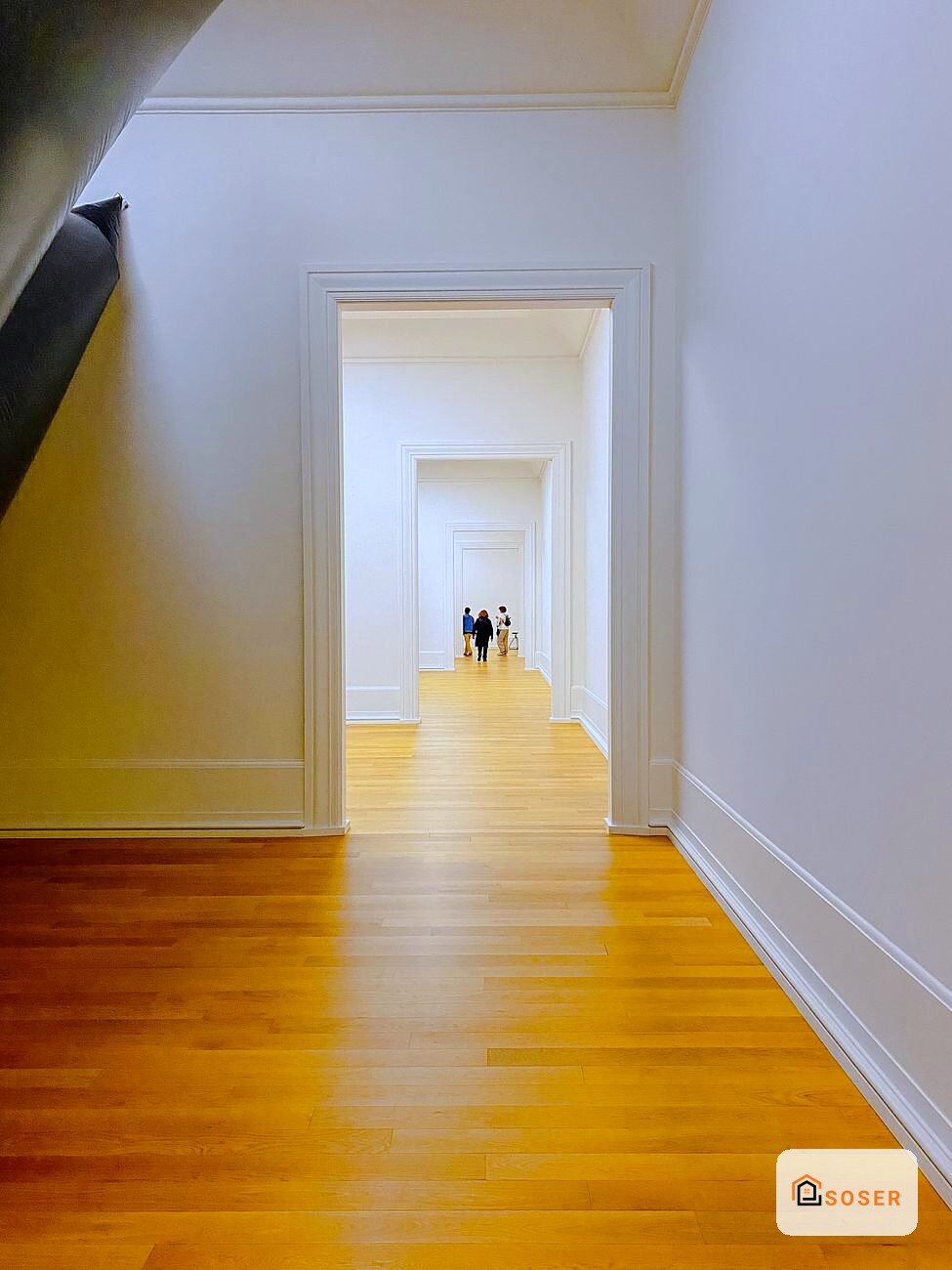 Corridoio moderno con pavimento in legno e pareti bianche, prospettiva con porte allineate