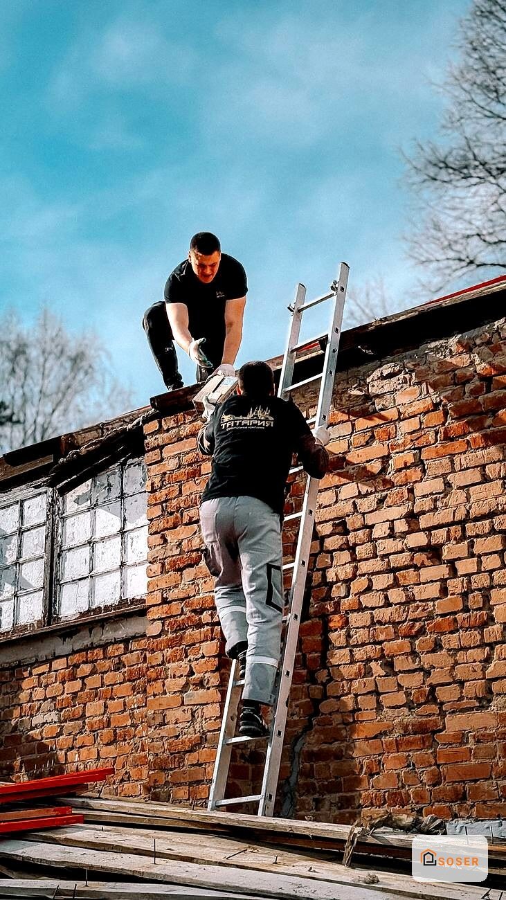 Operai in fase di ristrutturazione tetto in laterizio con scala e ponteggio