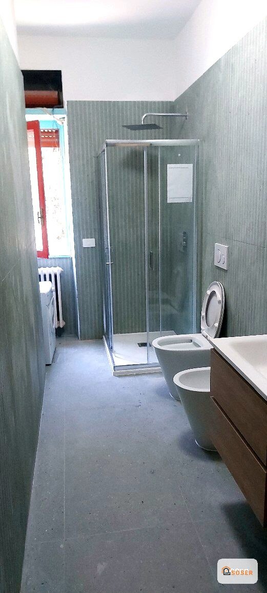 Bagno moderno ristrutturato con doccia in vetro, rivestimento in piastrelle grigie e sanitari bianchi