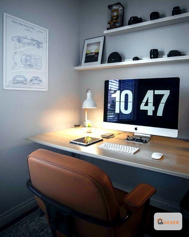 Scrivania moderna in legno con monitor, lampada da tavolo e scaffali bianchi in una cameretta grigia