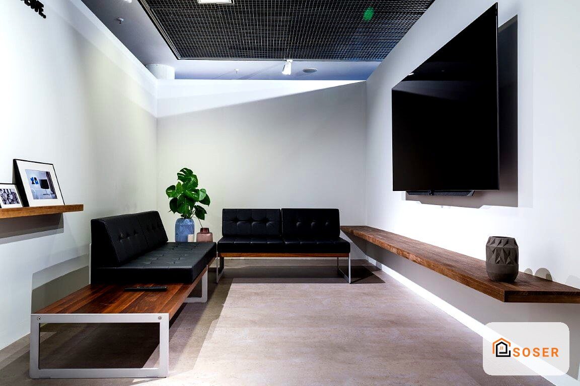 Sala riunioni moderna con pareti bianche, controsoffitto nero, divani neri e rivestimenti in legno